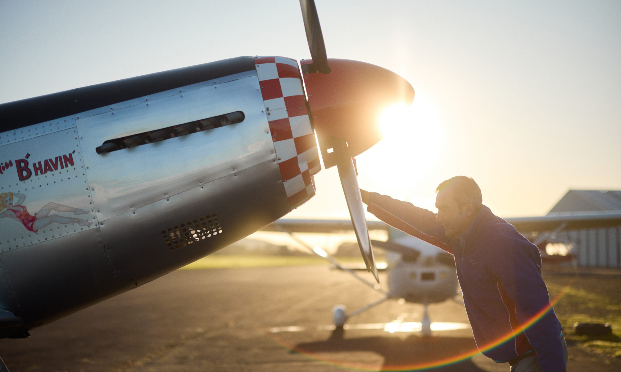 Man holding propeller for Ardmore War Birds plane with sunset