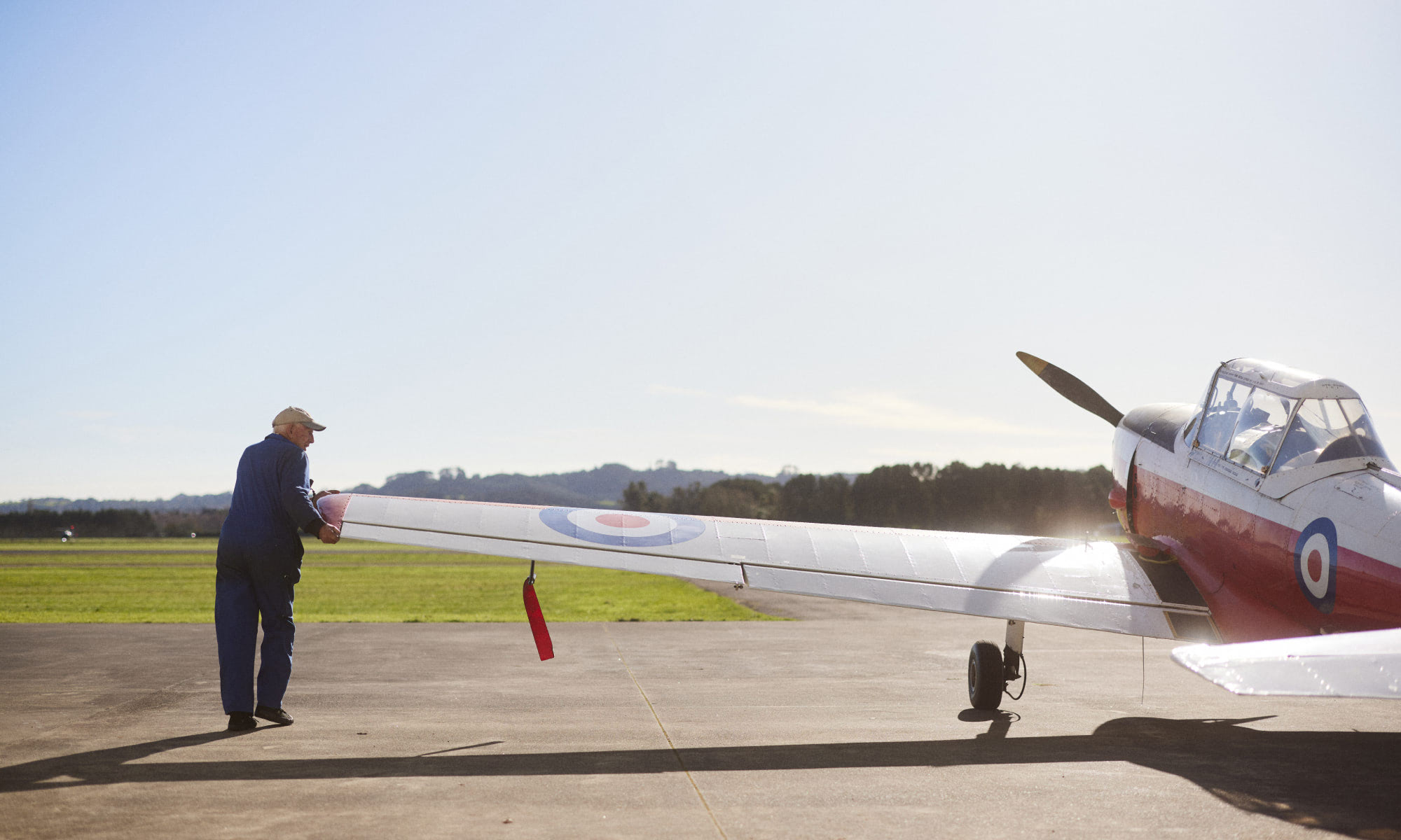Man holding wing on New Zealand War Bird plane on the runway