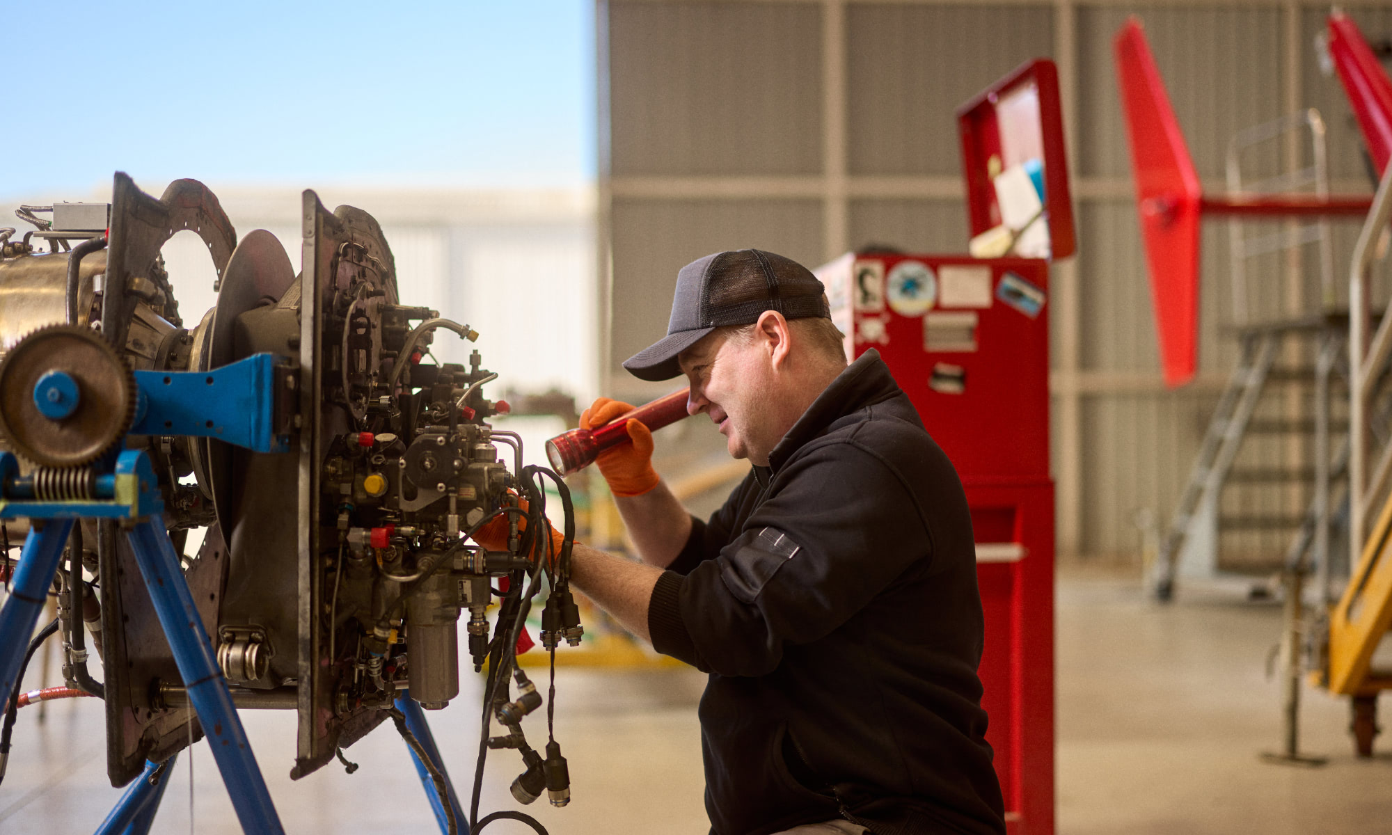 Ardmore male aviation technician working on engine with tool box in the background