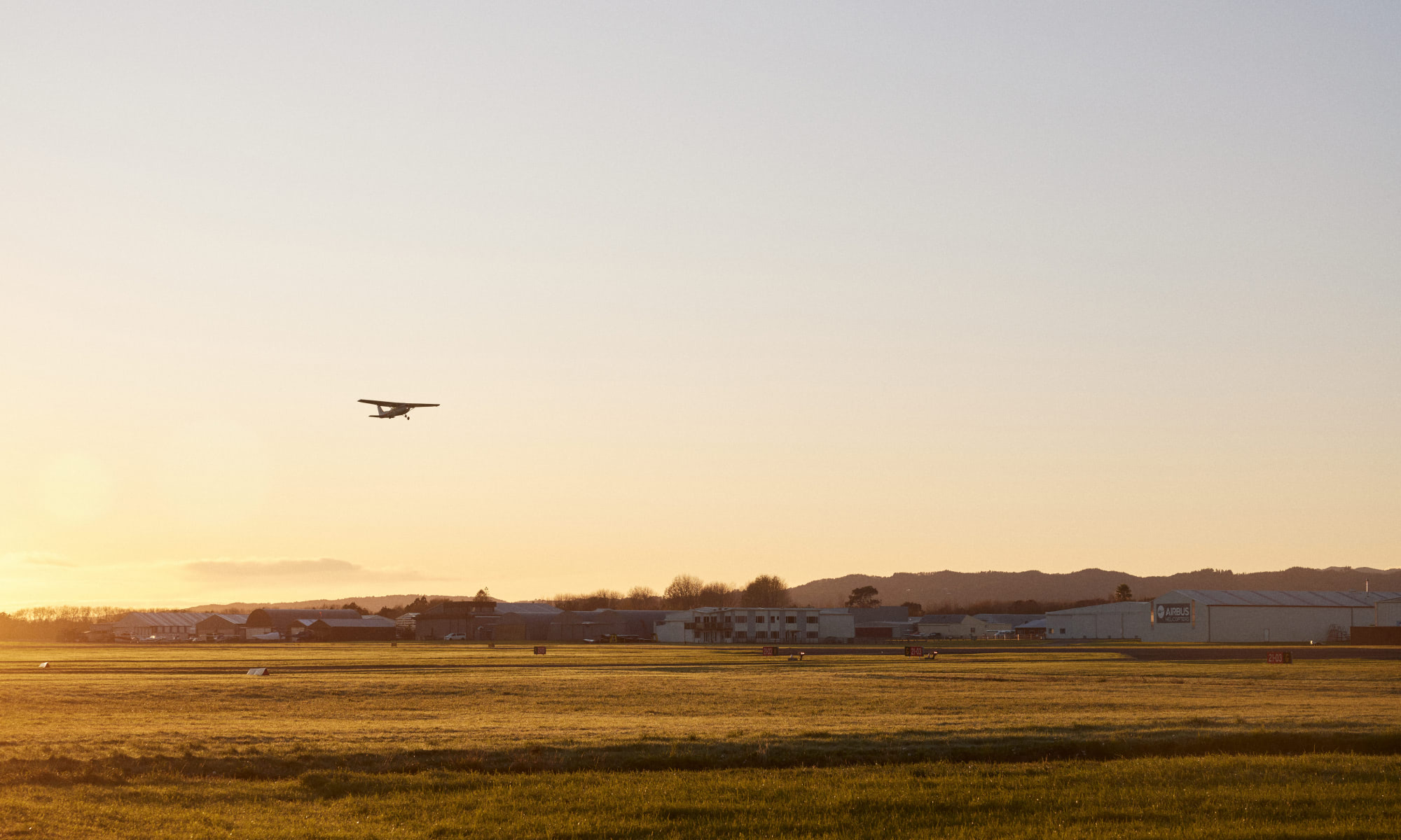 Plane flying in sunset above runway