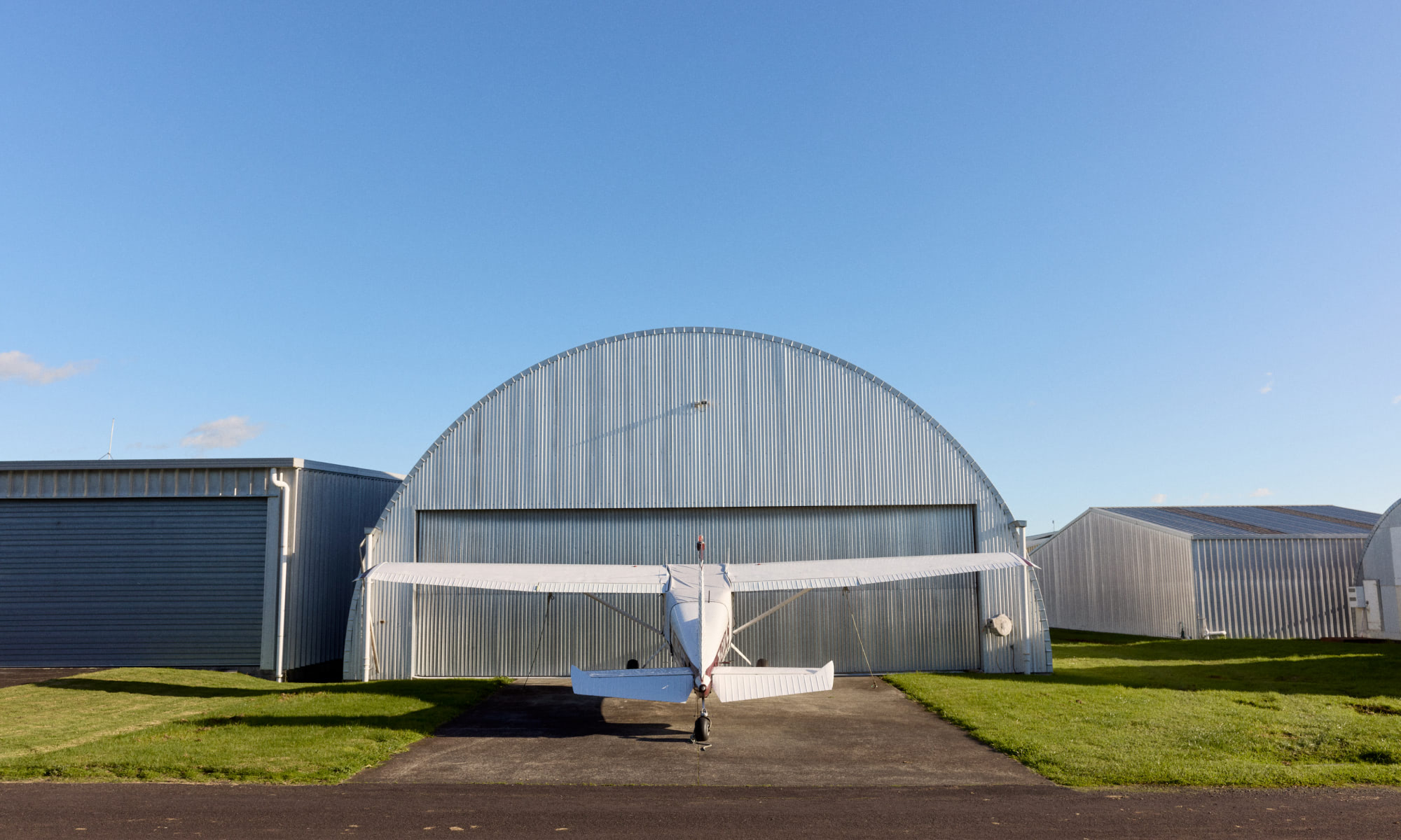 Plane outside hangar on clear sunny day