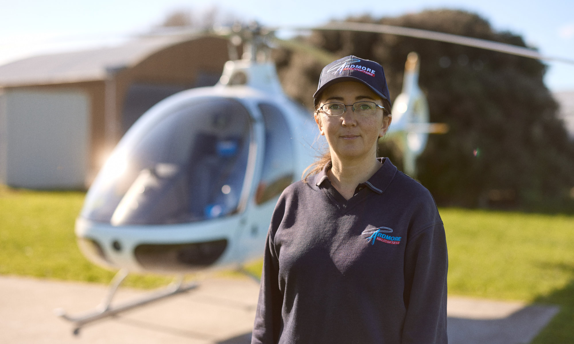 Woman standing in front of helicopter, wearing Ardmore Helicopters uniform